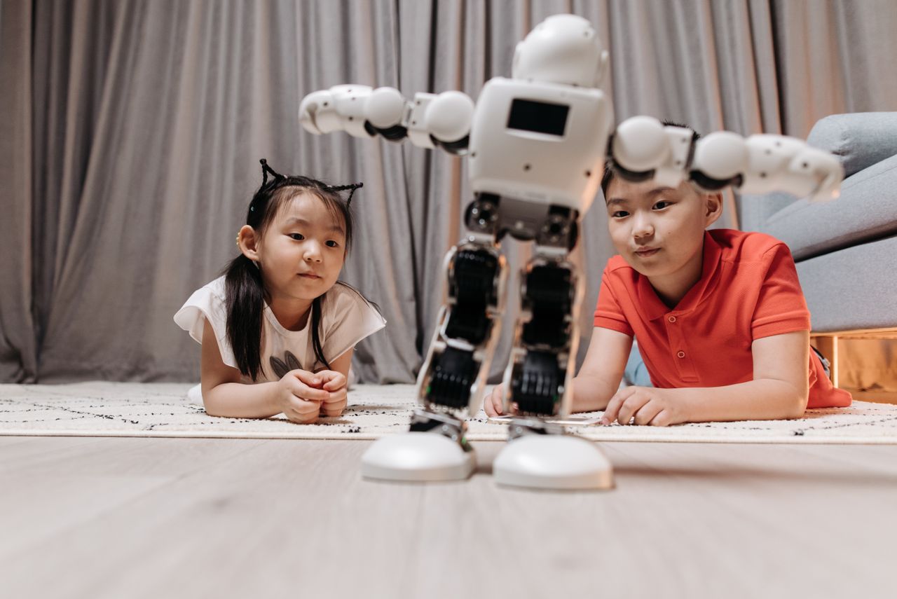 Services Children enjoying playtime with a modern android robot on a rug indoors.